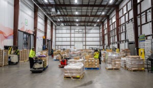 Moving pallets in a cold storage facility. Cold food storage warehouse. Food distribution center.